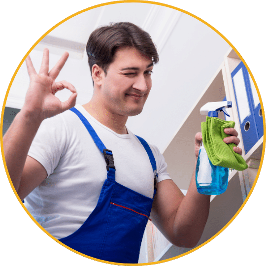 Junger Mann in blauem Overall mit Reinigungsmitteln und OK-Zeichen, vor hellem Hintergrund