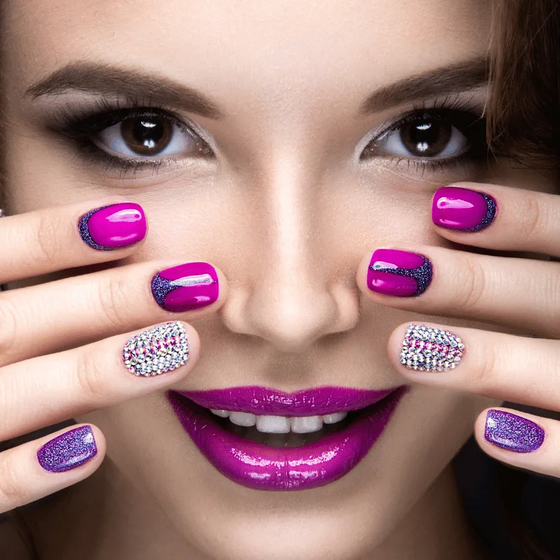 Nahaufnahme Gesicht einer Frau mit magentafarbenen und glitzernden Nägeln in verschiedenen Designs