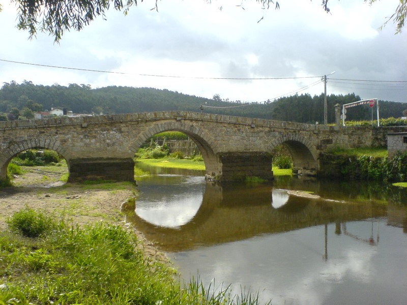 Steinbogenbrücke über Fluss in Portugal mit Wald und grünen Wiesen, Camino Portugues Reiseführer