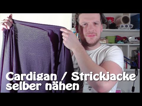 Mann präsentiert eine gefaltete lila Strickjacke vor seiner Brust