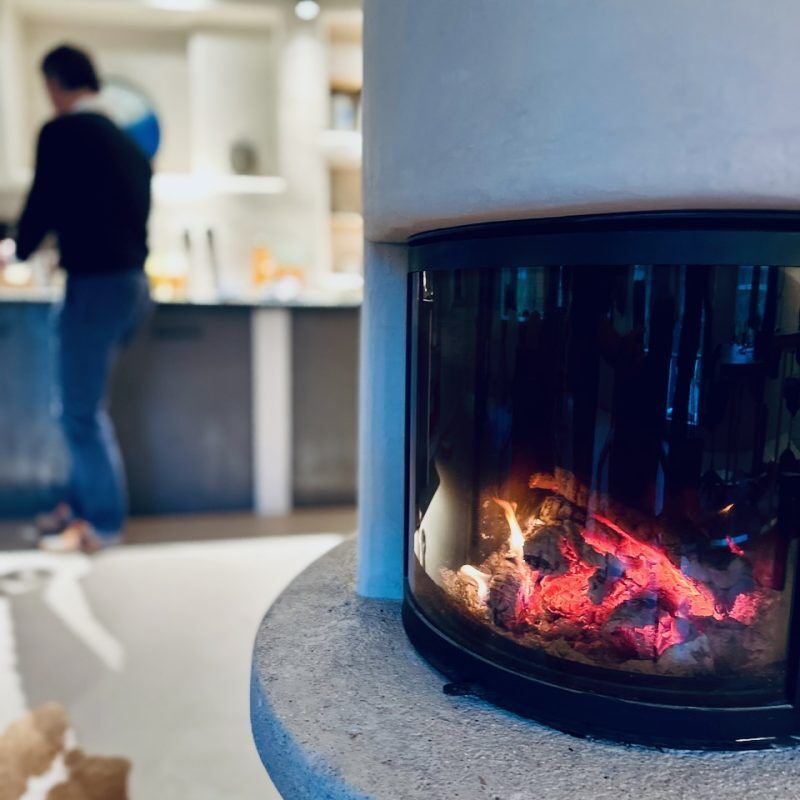 CEO Growth Mentoring – Coaching zur Unternehmensskalierung 3 Nahaufnahme eines modernen Elektrokamins mit Flammen, unscharfes Wohnzimmer im Hintergrund