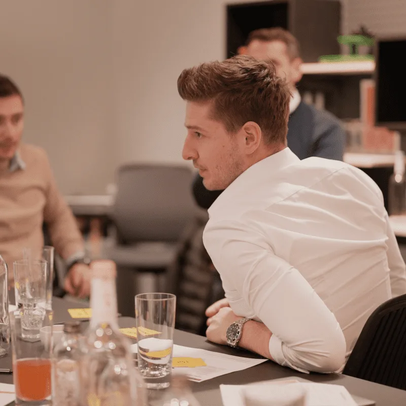 CEO Growth Mentoring – Coaching zur Unternehmensskalierung 19 Mann in weißem Hemd beim Workshop diskutiert mit anderen Teilnehmern