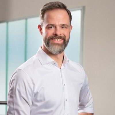 CEO Growth Mentoring – Coaching zur Unternehmensskalierung 28 Porträt von Jürgen Willmann in hellem Hemd vor modernem Büro-Hintergrund mit Glaswand