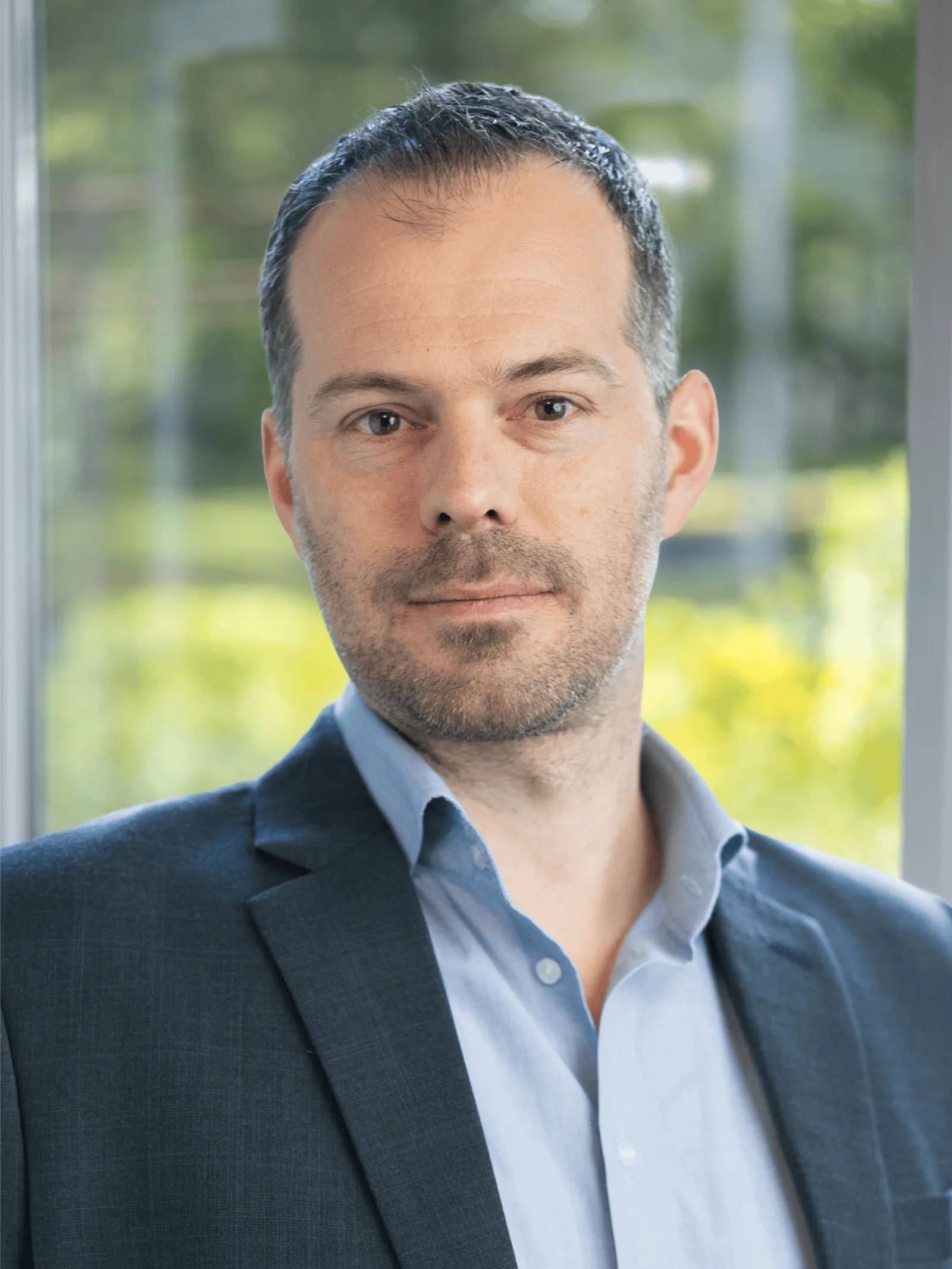 CEO Growth Mentoring – Coaching zur Unternehmensskalierung 16 Porträt von Rafael Waber, Scale-up Coach, Sakko über hellblauem Hemd vor Fenster