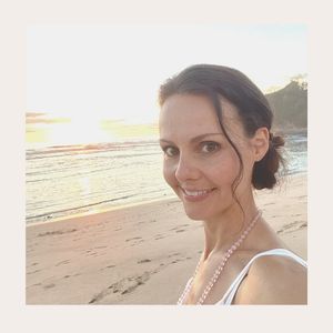 Corinna am Strand, lächelnde Frau mit Mala-Kette um den Hals