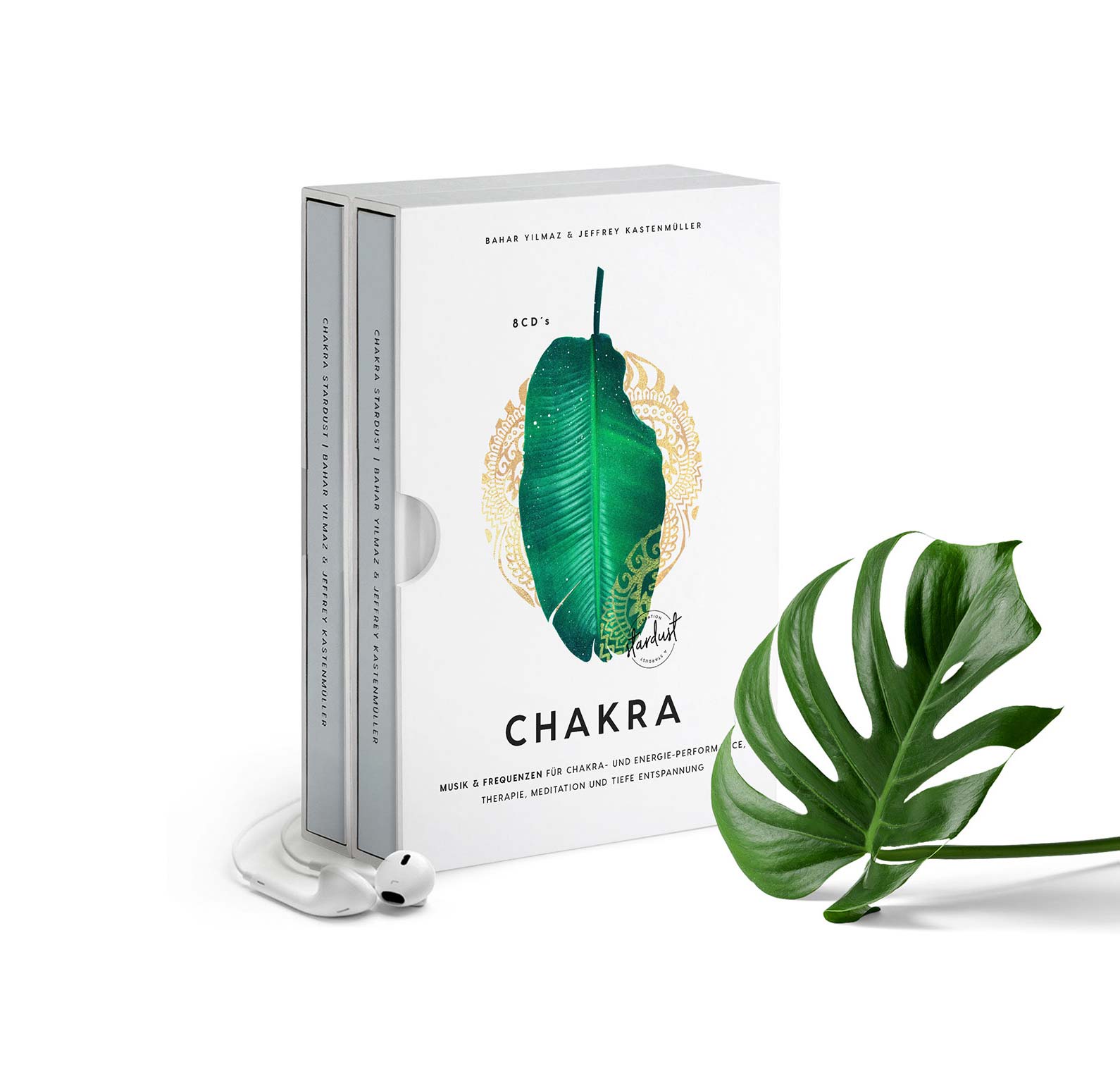 CD-Box Stardust mit zwei CDs, grünes Blatt-Motiv mit goldenem Ornament, weiße Verpackung, daneben grüne Monstera-Pflanze