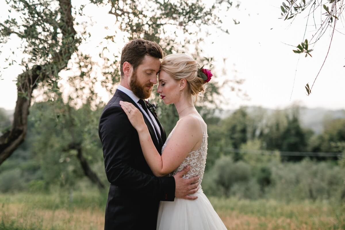 Hochzeitspaar in eleganten Kleidern in grüner Naturlandschaft, küssend und umarmend