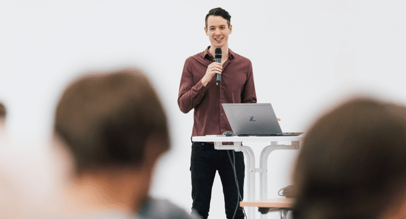 Referent hält Vortrag mit Mikrofon vor Publikum im Seminar