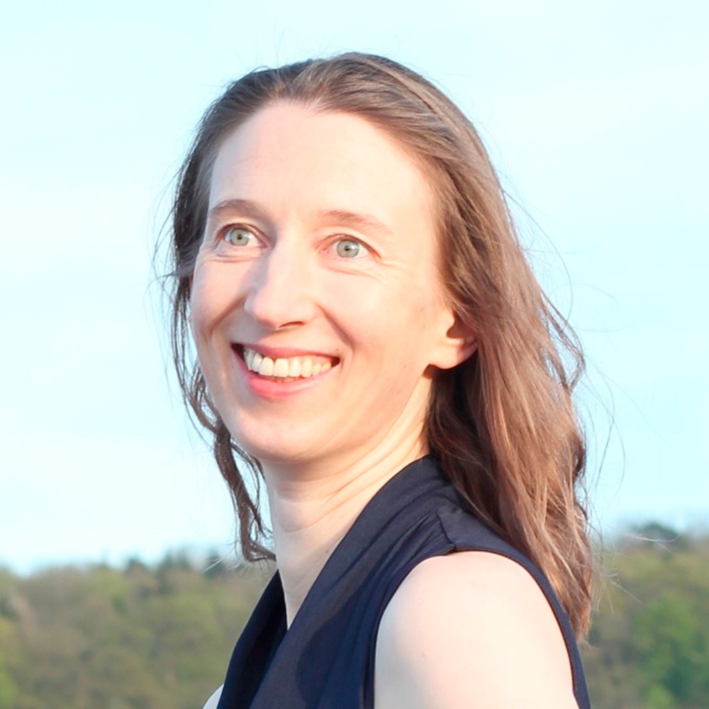 Chlorophyllkongress – Videokongress über Blattgrün von Maria Kageaki 12 Porträt einer lächelnden Frau mit rötlichem Haar gegen hellen Himmel und grünes Hügelland