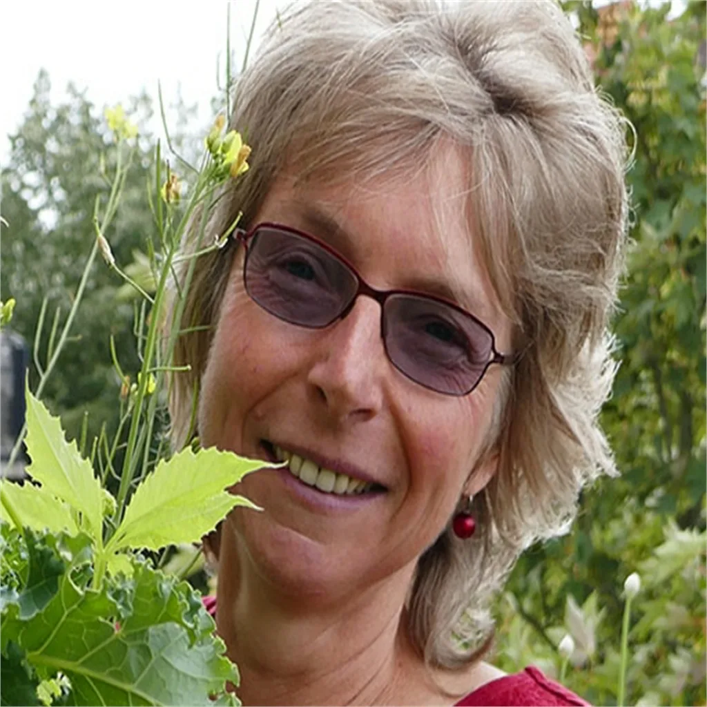 Chlorophyllkongress – Videokongress über Blattgrün von Maria Kageaki 20 Birgit Schattling, Frau mit Brille zwischen grünen Pflanzen und Kräutern im Garten