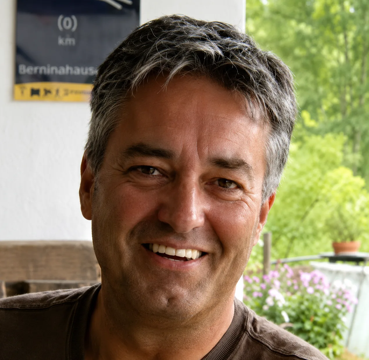 Chlorophyllkongress – Videokongress über Blattgrün von Maria Kageaki 24 Schorsch Kössel, Mann mittleren Alters vor grünem Hintergrund mit Blüten, lächelnd