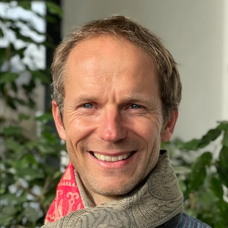 Chlorophyllkongress – Videokongress über Blattgrün von Maria Kageaki 15 Marco Vonmoos, Mann mittleren Alters mit braunem Haar und grauem Schal vor grünem Hintergrund