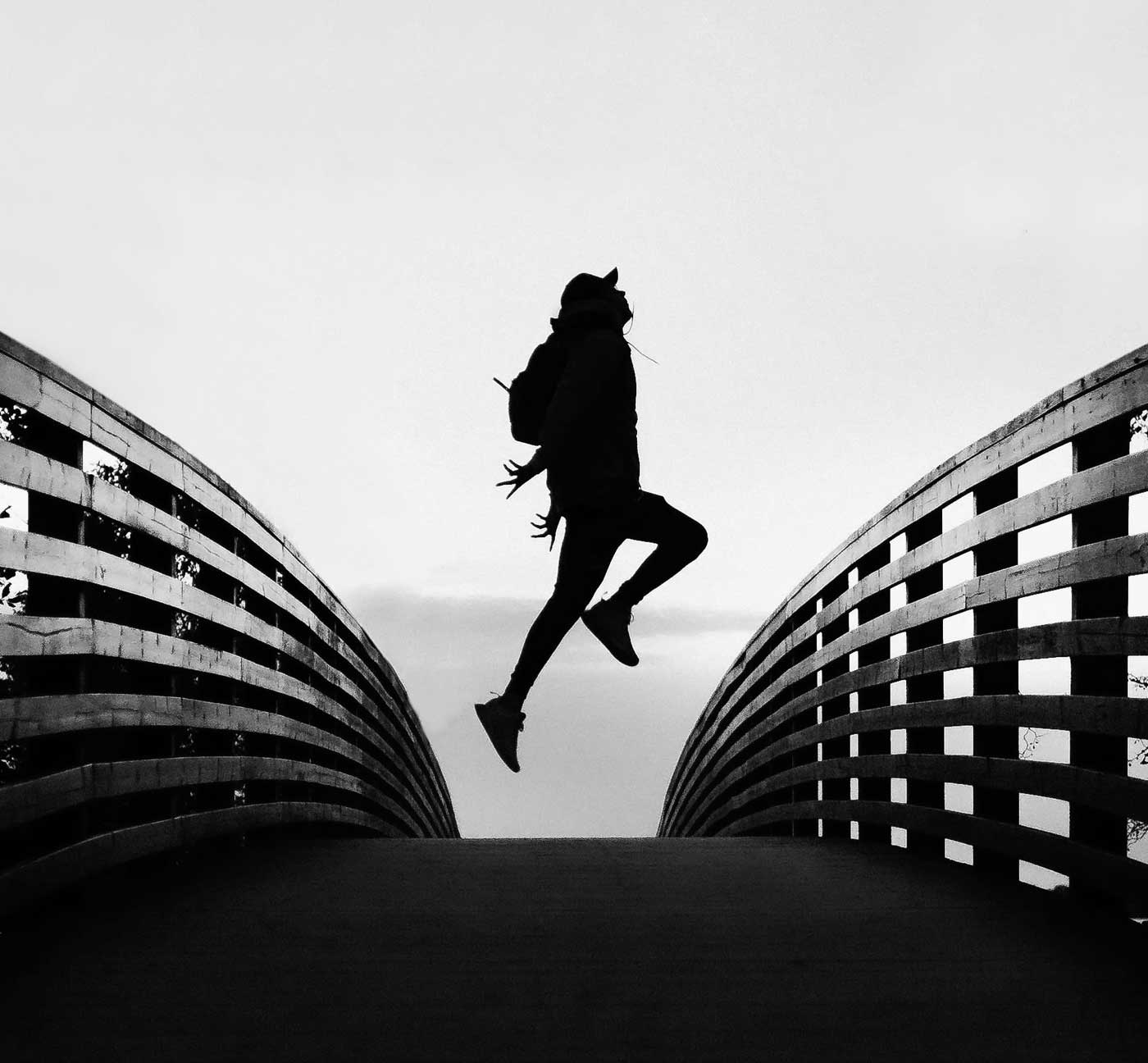 Schwarzweiß-Silhouette einer springenden Person zwischen zwei modernen Gebäuden