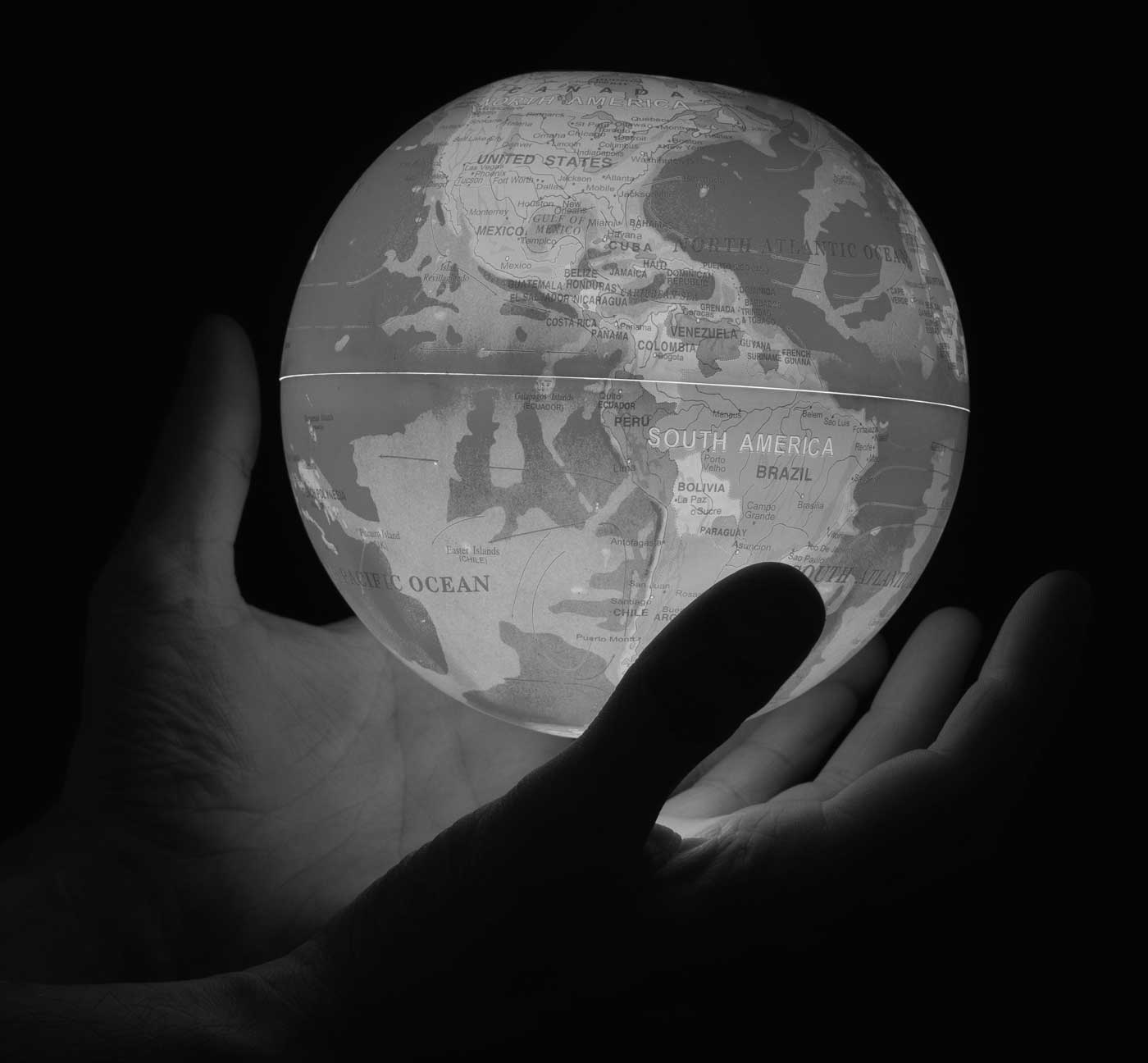 Hände halten leuchtenden Globus mit Kontinenten auf schwarzem Hintergrund