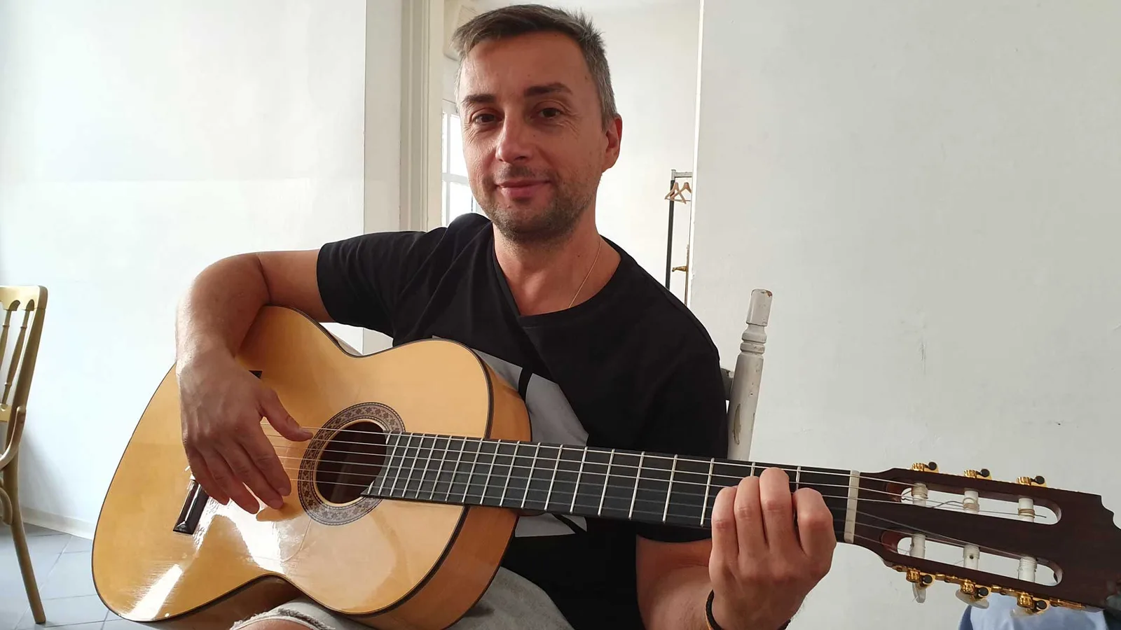 Mann mit schwarzem Shirt hält klassische Gitarre, spielt, Kundenstimme