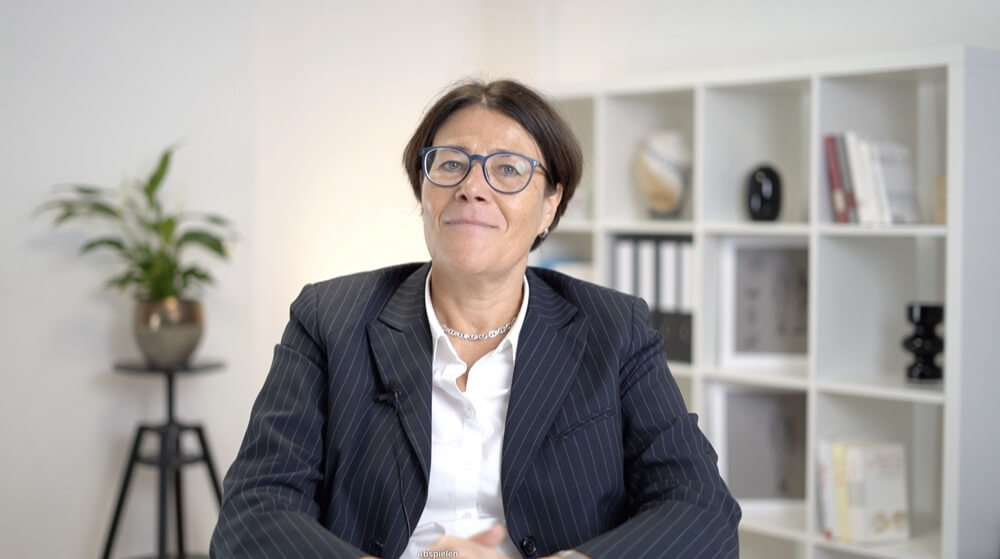 Frau mit Brille im pinstripe Anzug mit Bluse vor Wandregal