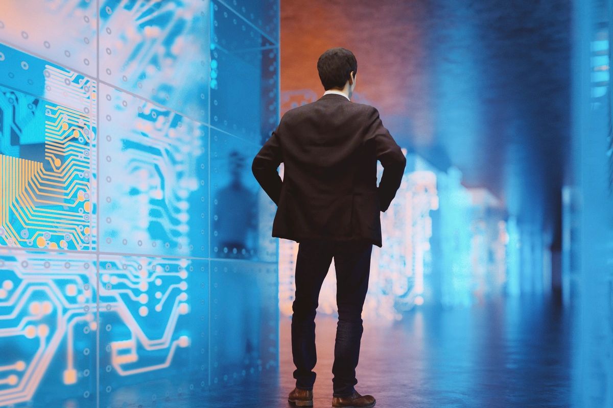 Geschäftsmann von hinten vor leuchtenden digitalen Schaltkreisen und technologischen Displays