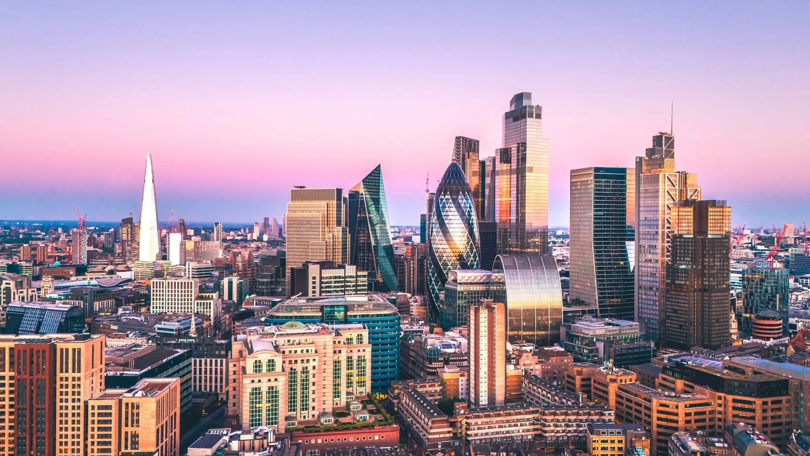 Skyline von London bei Sonnenuntergang mit beleuchteten modernen Hochhäusern