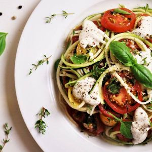Pasta Pomodoro mit Mozzarella, Tomaten und Basilikum auf weißem Teller
