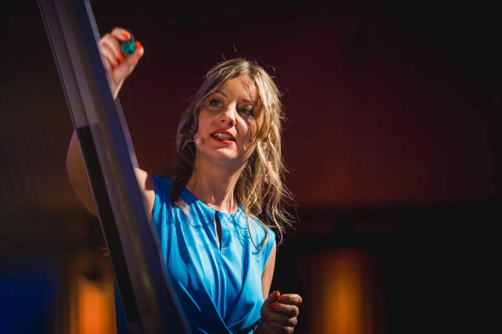 Julia Frisch hält bunte Bausteine, spricht auf Bühne in blauem Top