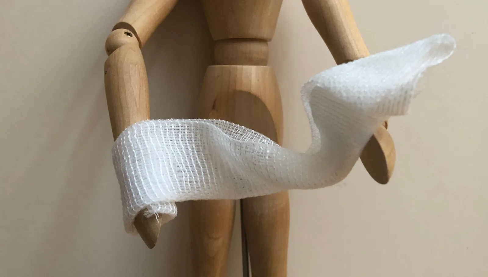 Hölzerne Anatomie-Figur mit Verbandage an Arm und Hand, Darstellung einer Verletzung