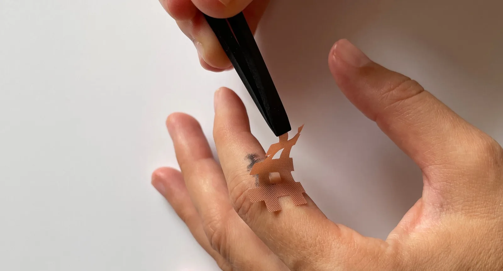 Hände mit Kinesio-Tape beim Auftragen auf Handfläche, therapeutische Anwendung