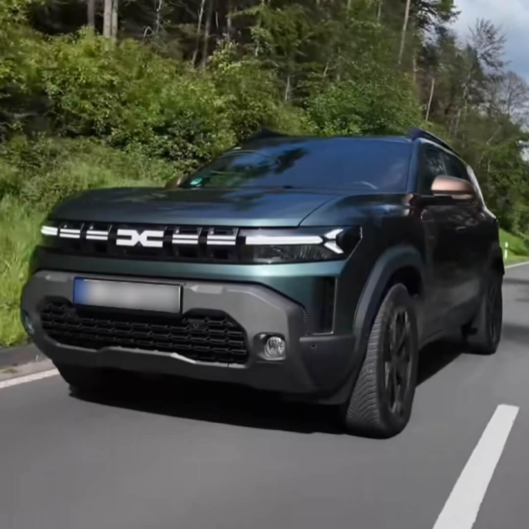 Dacia Duster in Grün-Grau auf Bergstraße, Frontalansicht mit LED-Scheinwerfern