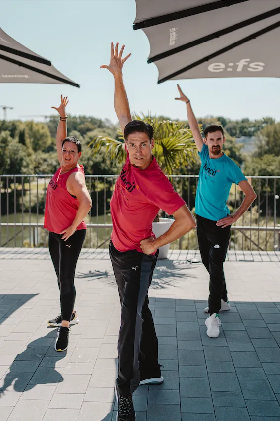 Drei Männer beim Tanzen auf Terrasse in colorful dancit Shirts