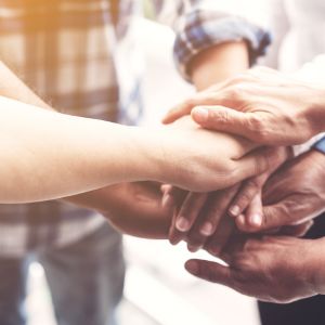 Mehrere Hände übereinander als Symbol für Gemeinschaft und Zusammenhalt