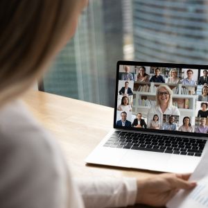 Frau vor Laptop mit Zoom-Videokonferenz mit mehreren Teilnehmern