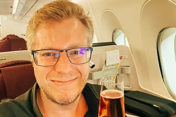 Fabian Hilpert mit Brille im Flugzeug mit Getränk