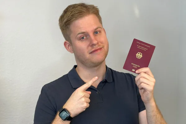 Robin Lerch hält deutschen Reisepass und zeigt auf diesen