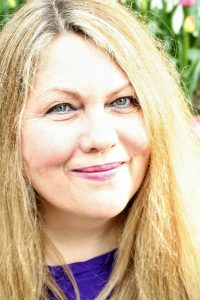 Portrait einer Frau mit langen blonden Haaren vor grünem Hintergrund
