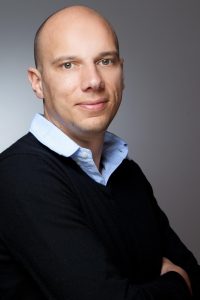 Portrait eines Mannes mit Glatze vor grauem Hintergrund