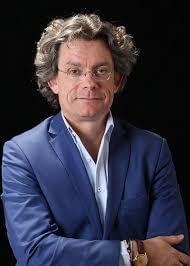 Portrait von Frank Sieren, Mann mit grauem Haar und Brille im dunkelblauen Anzug