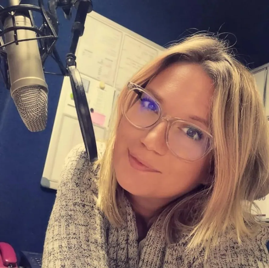 Junge Frau mit Brille am Aufnahmemikrofon im Studio
