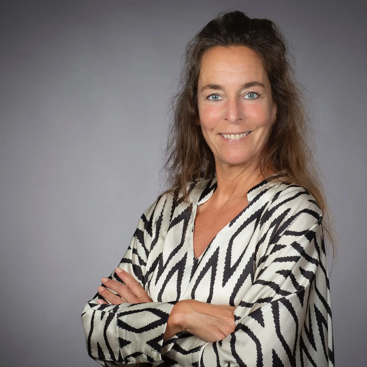 Portrait Stephanie Jeske mit Zebra-Muster Bluse vor grauem Hintergrund