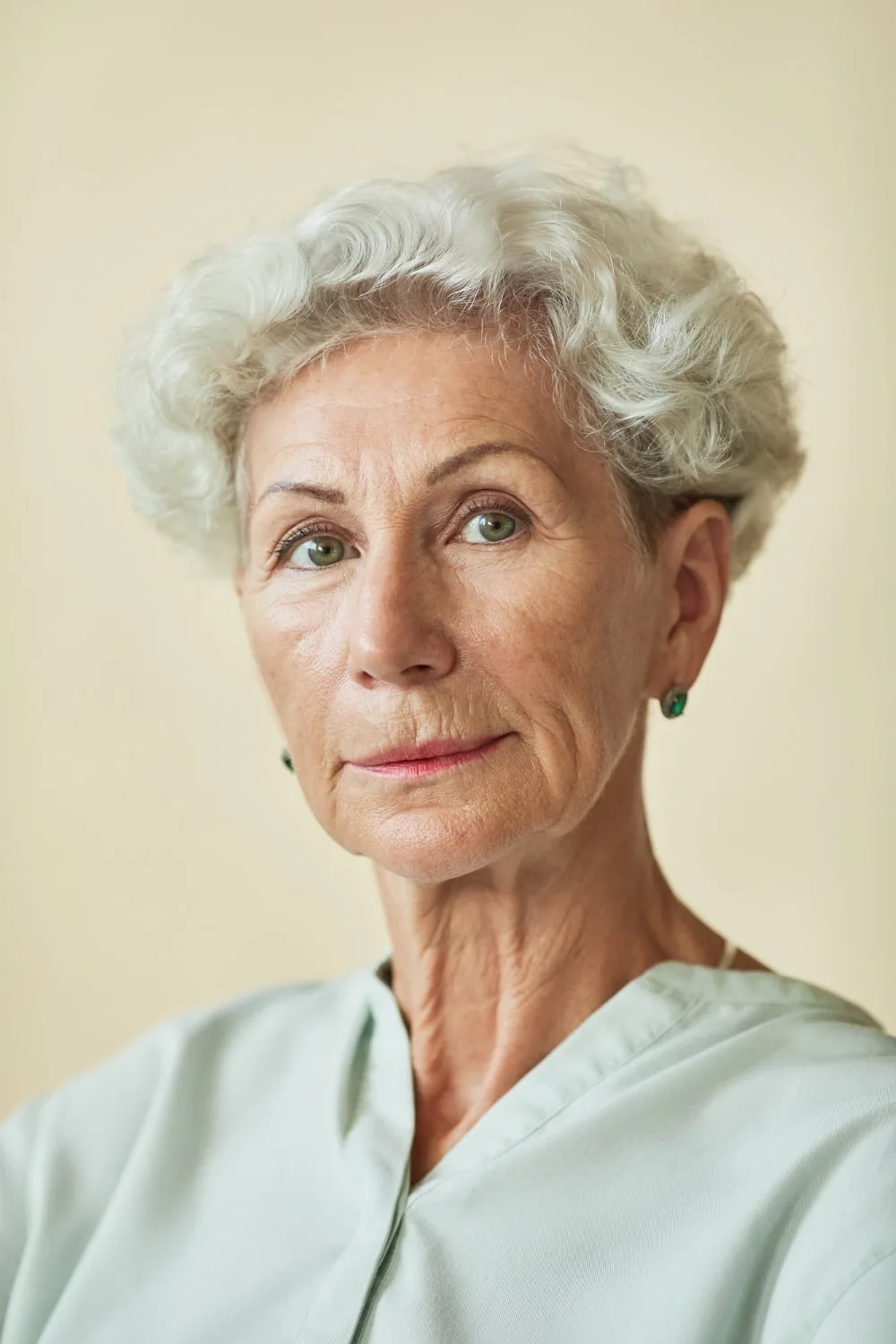 Porträt einer älteren Frau mit grauem Haar und grünen Ohrringen, Kundenstimme Rita L.