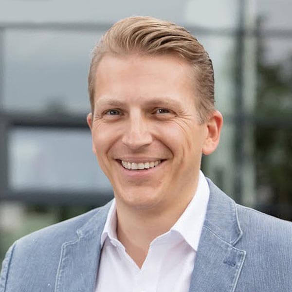 Tobias Beck, Sprecher, Portrait mit Blazer vor moderner Fassade