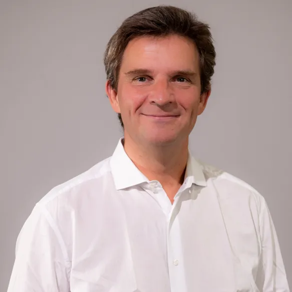 Porträt von Christian Burghardt im weißen Hemd vor grauem Hintergrund