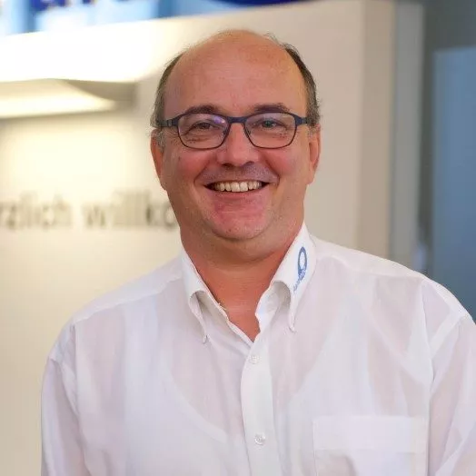 Dr. Simon Feldhaus, Sprecher, Portrait mit Brille und weißem Hemd