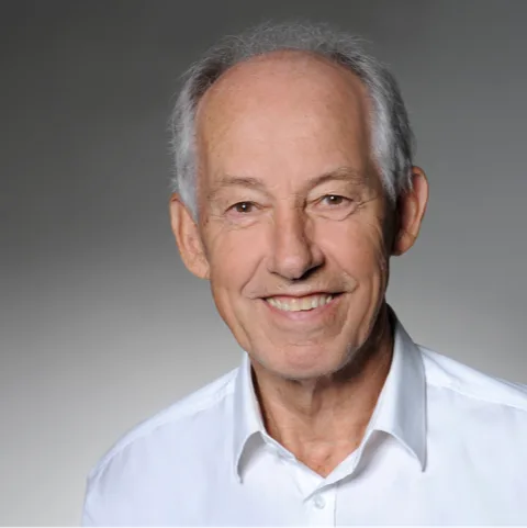 Jürgen Woldt Porträt, älterer Mann, graue Haare, weißes Hemd, neutraler grauer Hintergrund