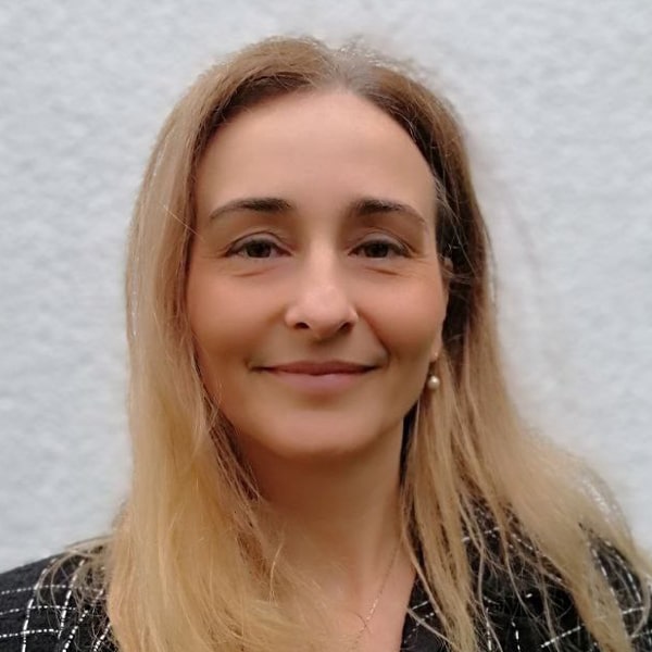 Mira Feist, blonde Frau mit schulterlangen Haaren vor weißem Hintergrund