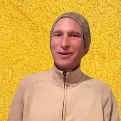 Mann in beigem Hoodie vor gelb strukturiertem Hintergrund