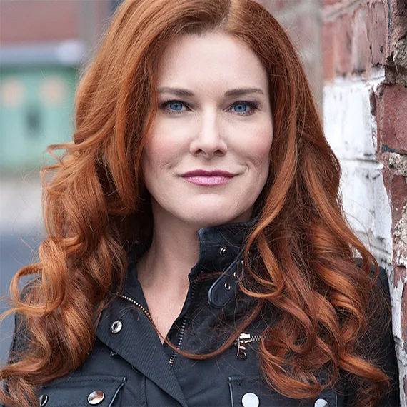 Tatjana Strobel Porträt, lange rötlich-braune Haare, schwarze Lederjacke mit Reißverschlüssen, Backsteinwand