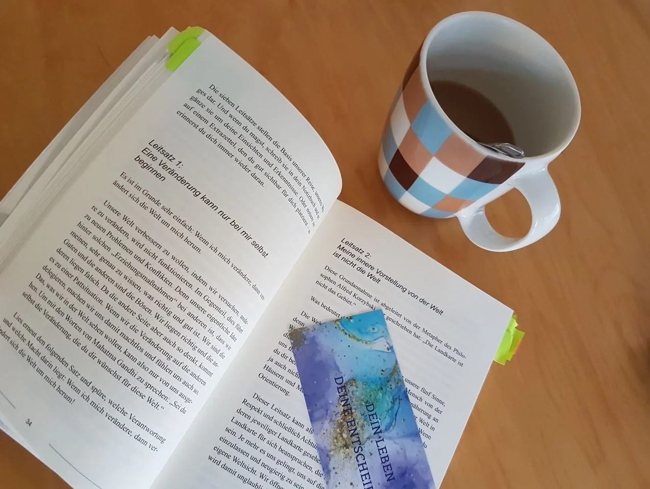 Aufgeschlagenes Buch mit Kaffeetasse zeigt Leseprobe und Übungen zur Anwendung
