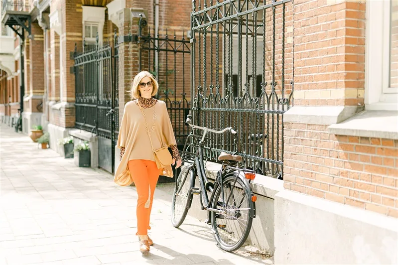 Porträt von Sabine Walter in beiger Poncho und oranger Leggings mit Fahrrad