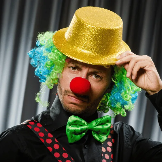 Mann verkleidet als Clown mit gelbem Hut grüner Perücke roter Nase