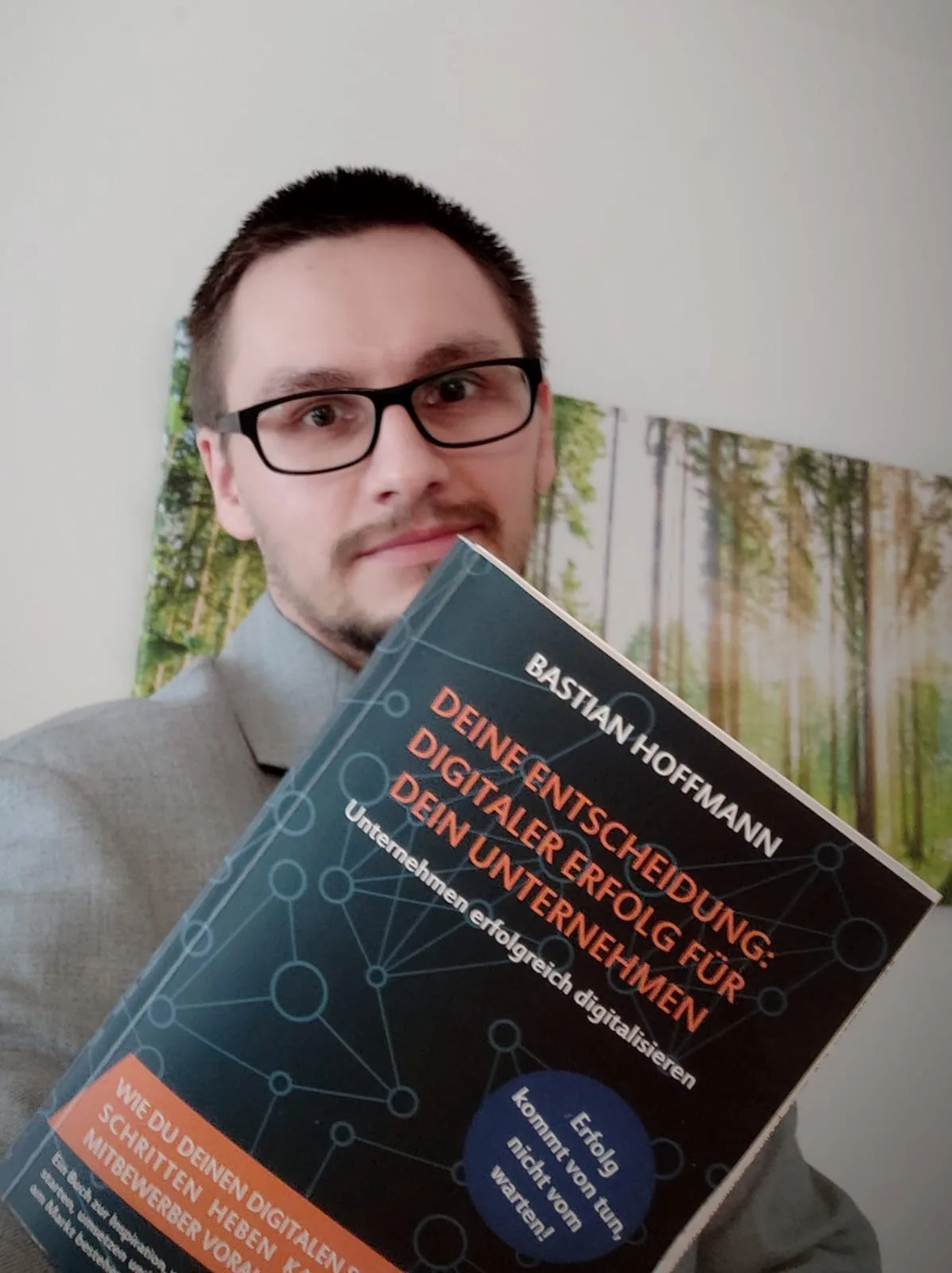 Mann mit Brille hält Buch vor sich, Portrait mit Natur-Hintergrund