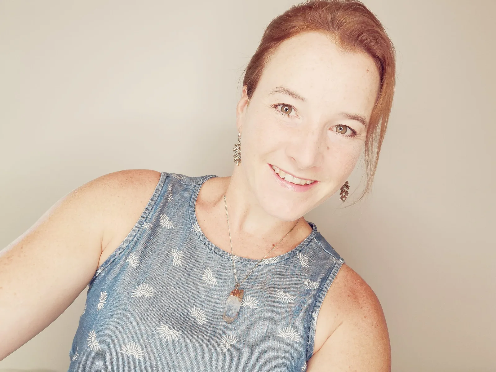 Porträt von Simone White mit rötlichen Haaren, lächelnd, in Denimtop mit Sonnenmotiven